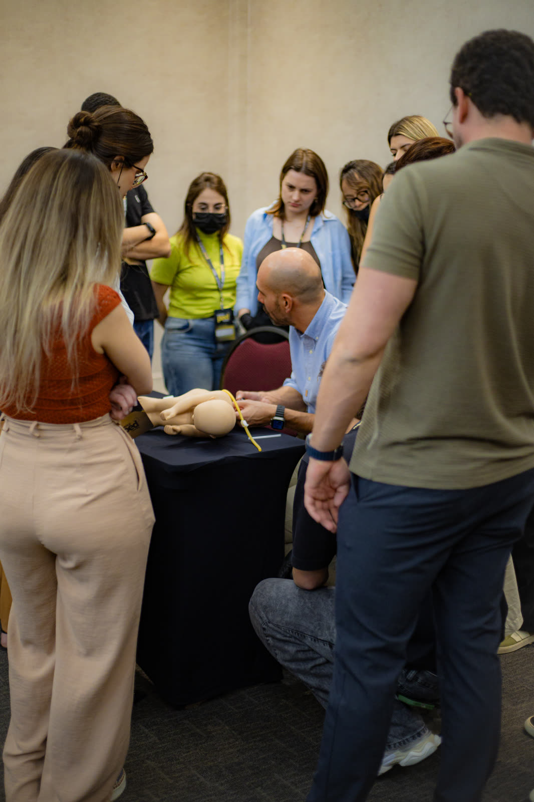 Dr. Marcos demonstrando procedimento com simulador pediátrico em grupo